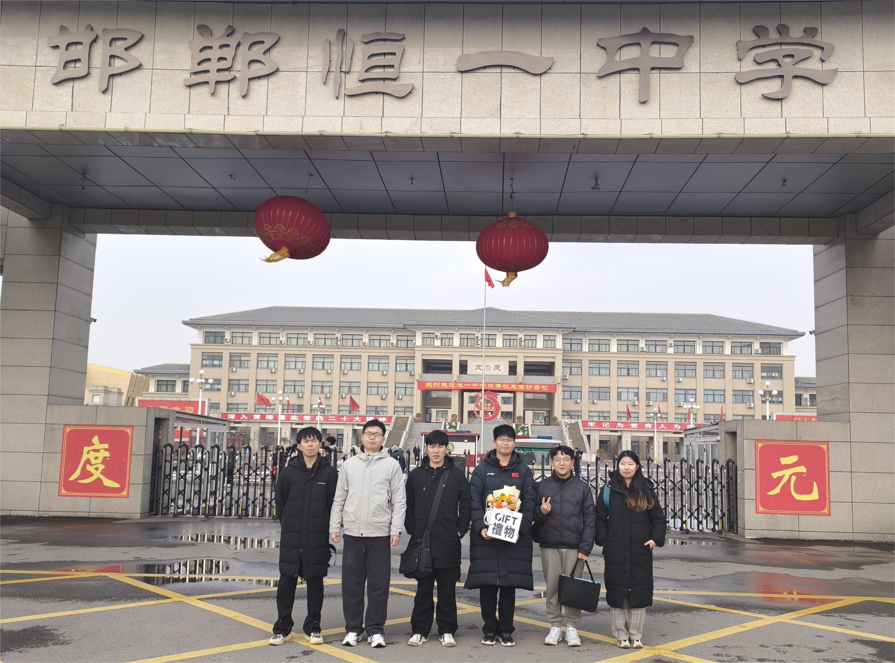 图为团队成员在高中校门处合影.jpg